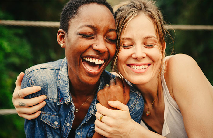 two women hugging, smiling, and laughing together